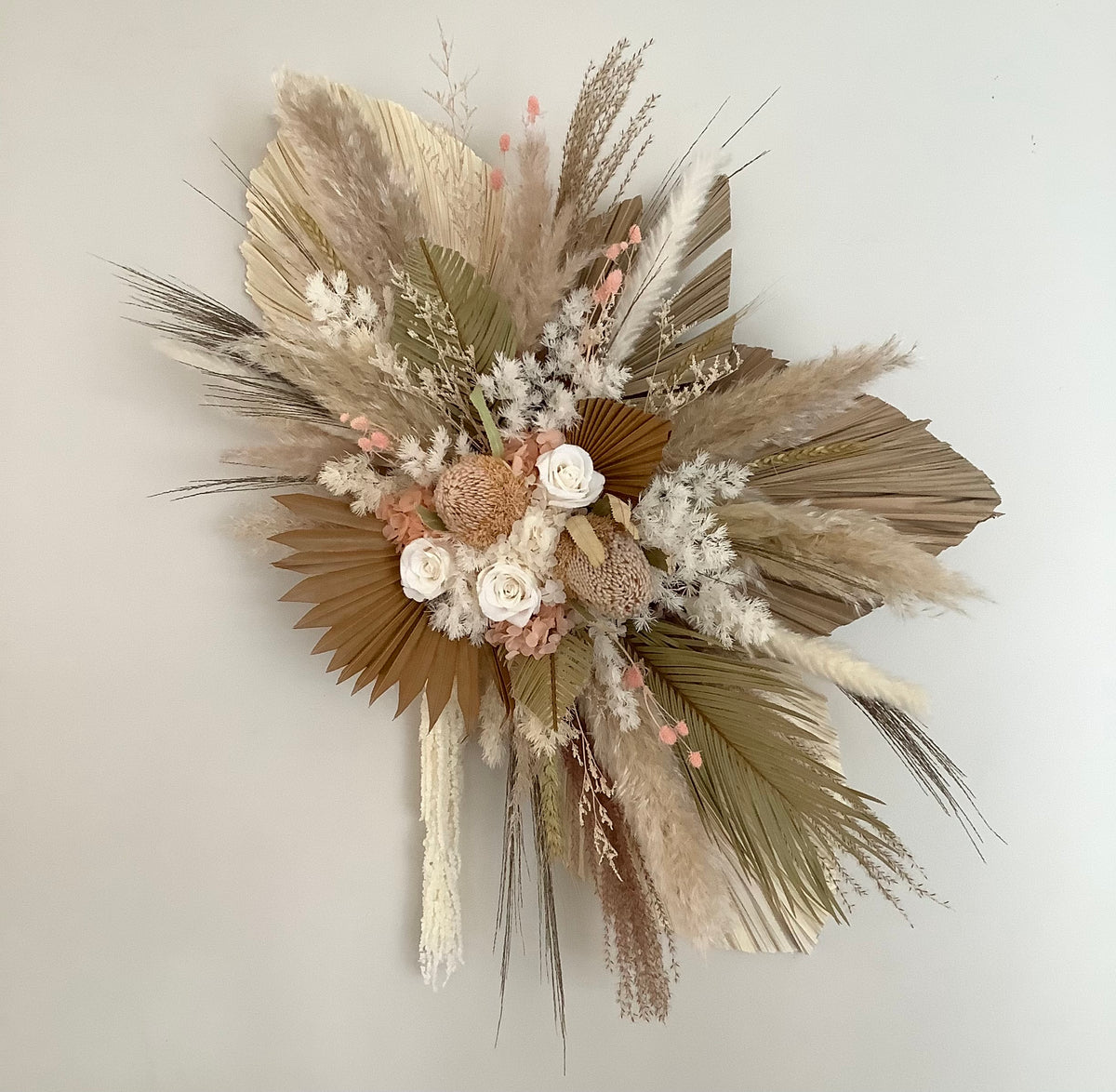 Dried and preserved wall hanging arrangement using a variety of palm leaves and flowers